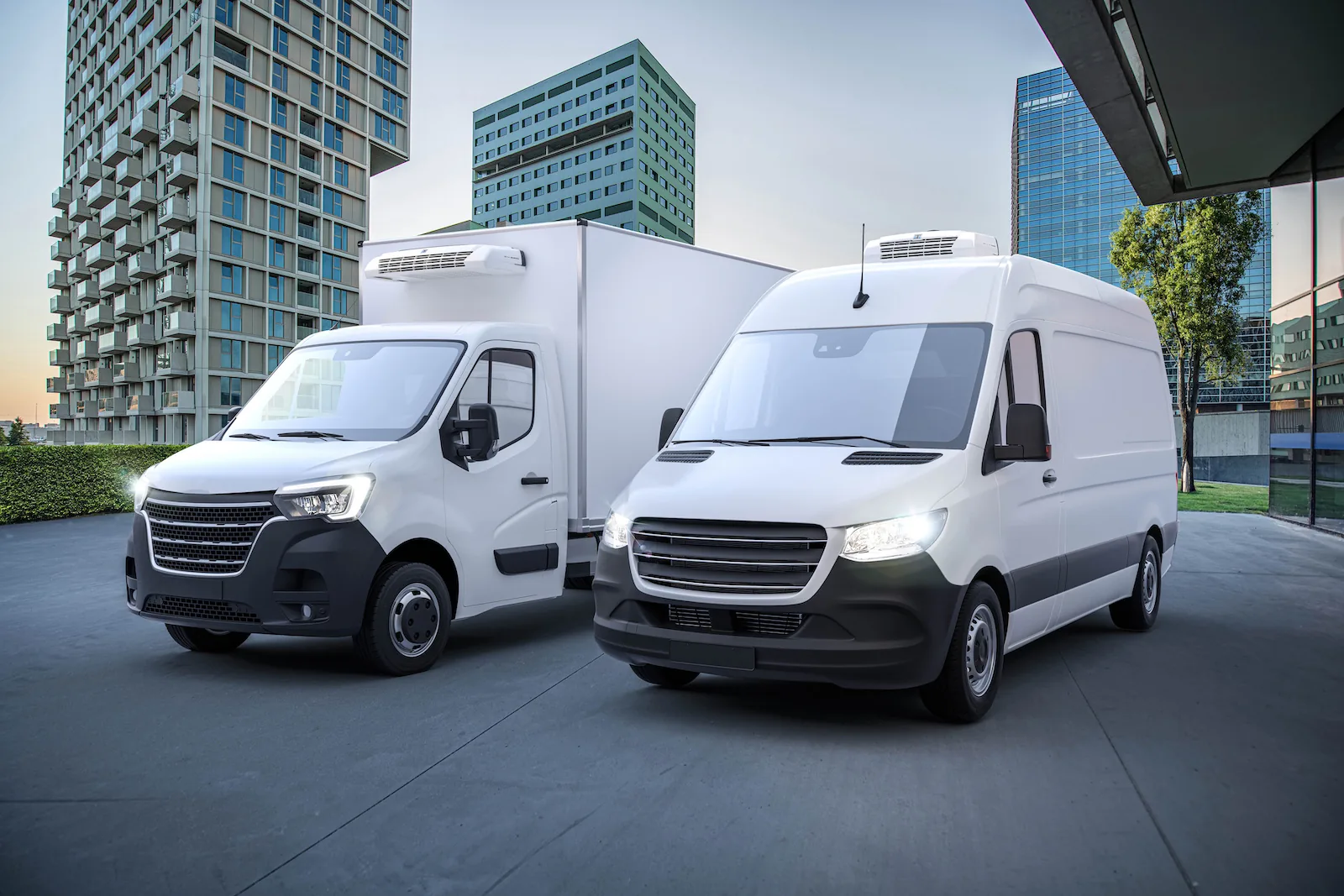 White refrigerated cargo van and box truck staged for reefer installation planning